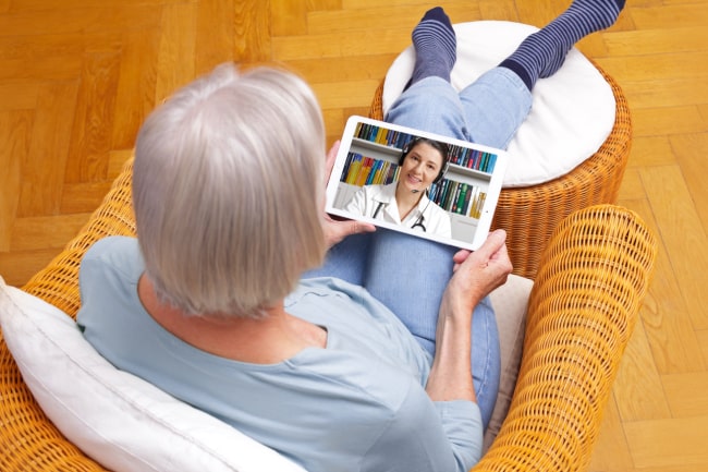 elderly lady video chatting a doctor through her tablet